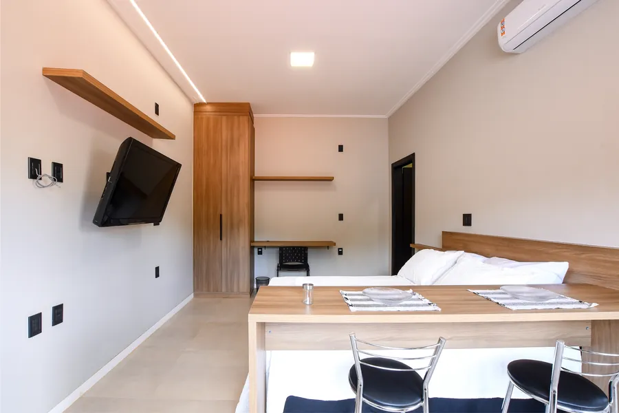 Ambiente mobiliado com cama, mesa e bancada de trabalho.