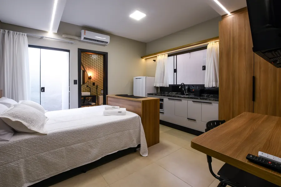 Cama, cozinha e bancada em um ambiente integrado.
