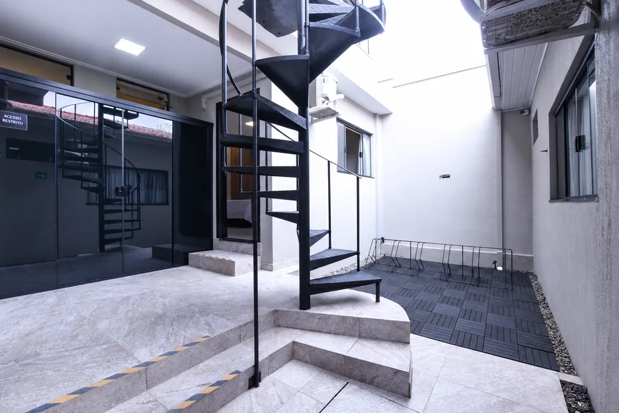 Área externa com escada metálica, bicicletário II e deck modular preto.