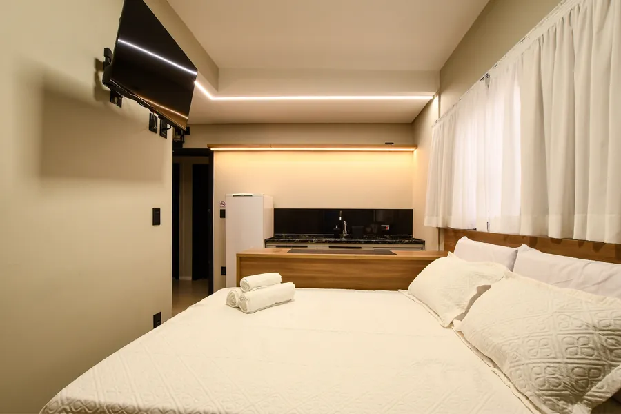 Cama, bancada de refeições e cozinha no mesmo ambiente.