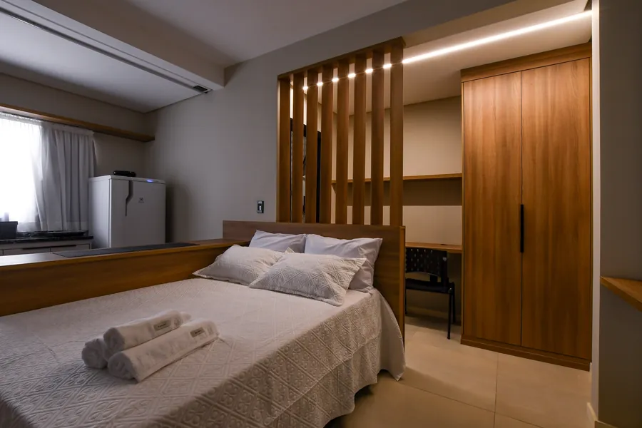 Enxoval branco, marcenaria e iluminação indireta.